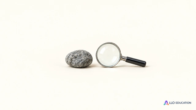 Un petit galet gris et une loupe neutre entièrement visibles sur fond ivoire.